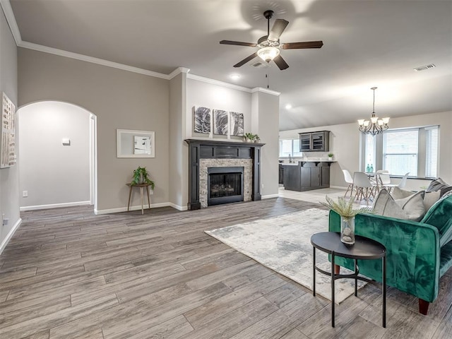 living area with arched walkways, a fireplace, visible vents, baseboards, and light wood finished floors