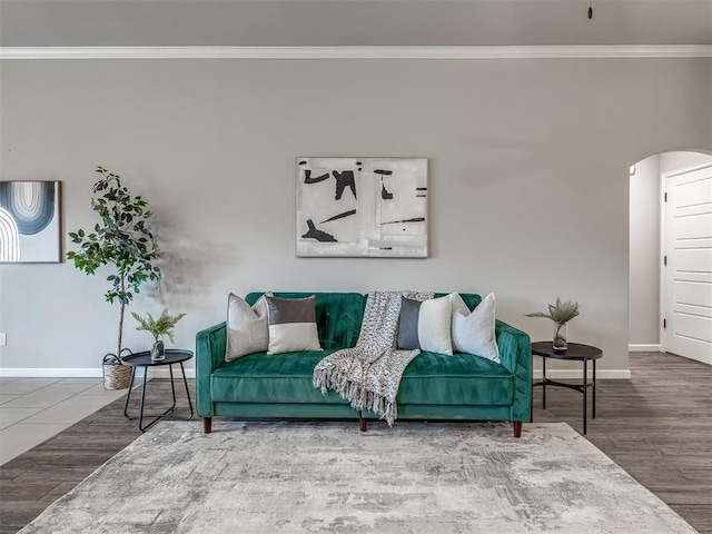 living area featuring ornamental molding, arched walkways, baseboards, and wood finished floors