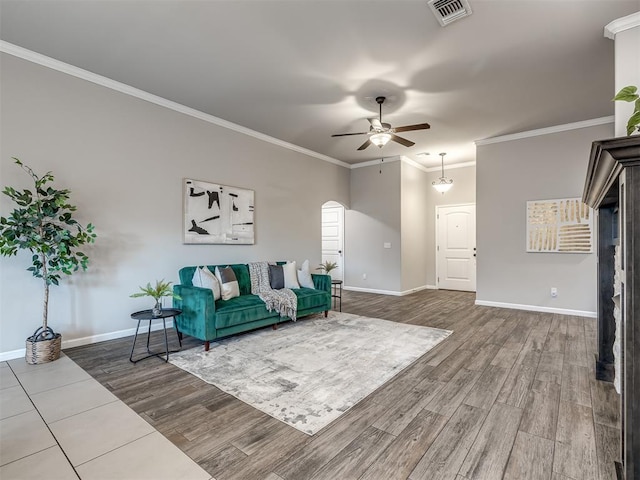 living room featuring arched walkways, visible vents, baseboards, and wood finished floors