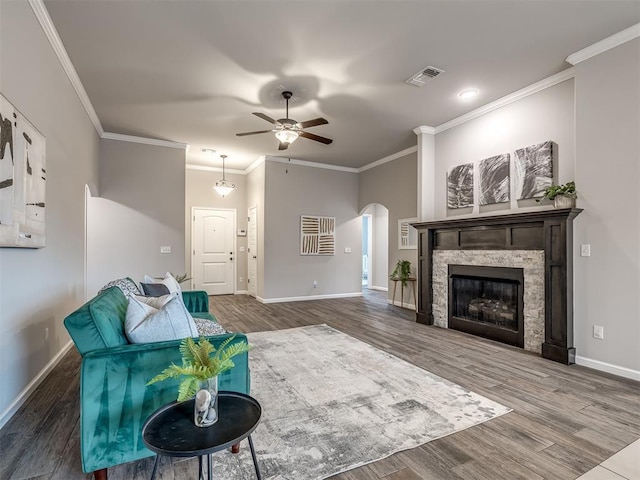 living area with baseboards, visible vents, arched walkways, wood finished floors, and crown molding