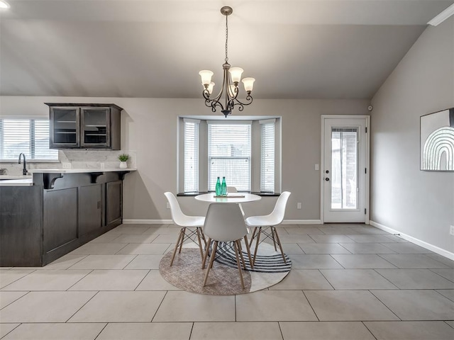 dining room featuring a notable chandelier, vaulted ceiling, baseboards, and light tile patterned floors