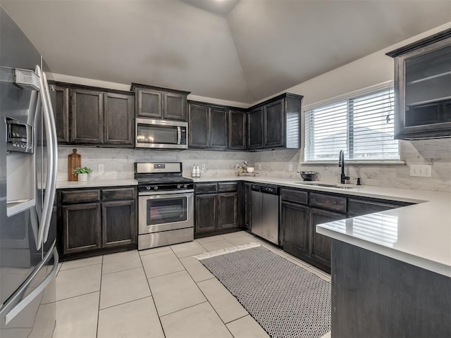 kitchen with light tile patterned floors, stainless steel appliances, light countertops, vaulted ceiling, and a sink