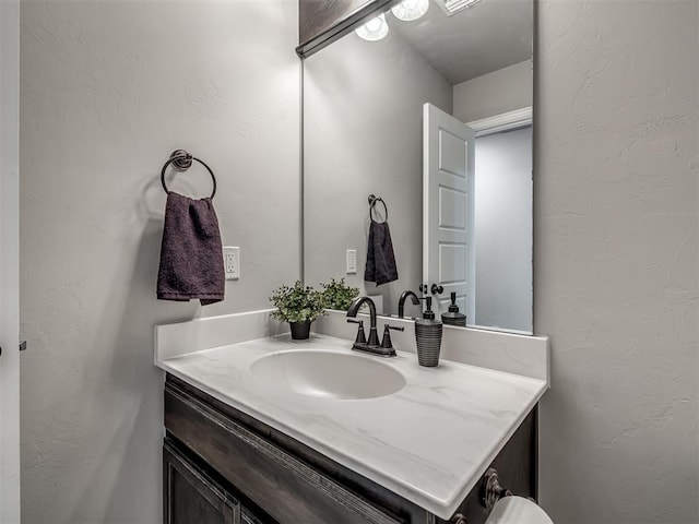 bathroom with a textured wall and vanity