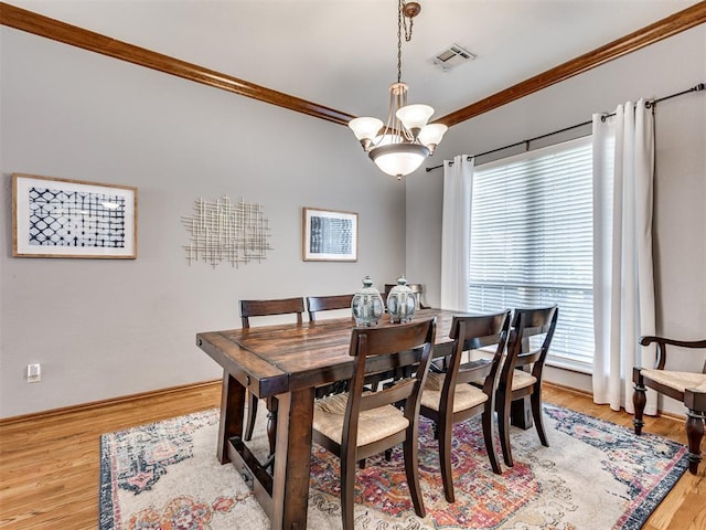 dining room with crown molding, an inviting chandelier, light hardwood / wood-style floors, and a wealth of natural light