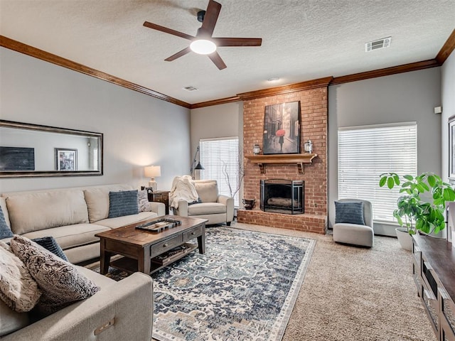 living room featuring carpet floors, ceiling fan, crown molding, a brick fireplace, and a textured ceiling