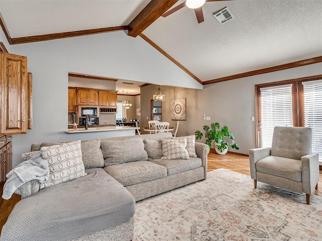 living room with crown molding, ceiling fan with notable chandelier, and vaulted ceiling with beams