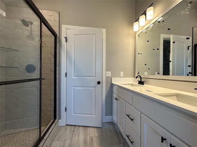 bathroom with a stall shower, a sink, baseboards, and double vanity