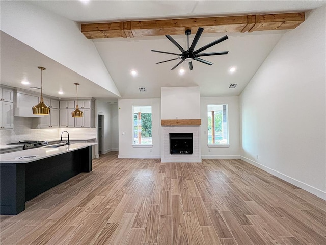 kitchen featuring a large island, ceiling fan, pendant lighting, light hardwood / wood-style floors, and decorative backsplash