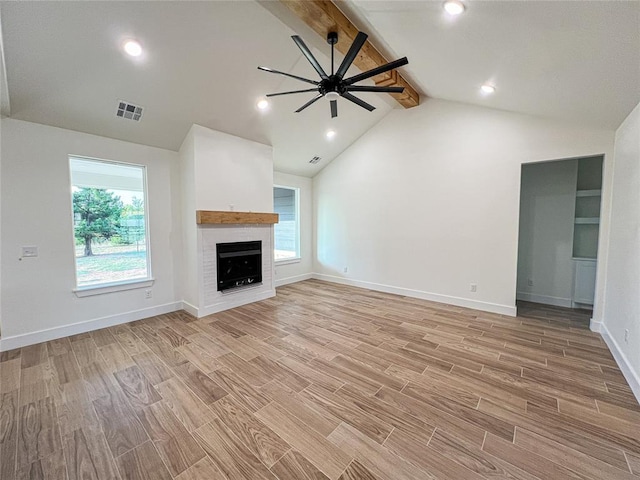 unfurnished living room with vaulted ceiling with beams, light hardwood / wood-style floors, a wealth of natural light, and a brick fireplace