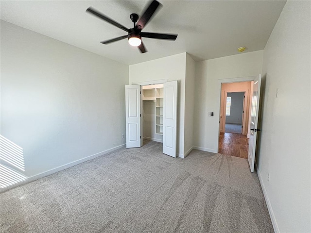 unfurnished bedroom with ceiling fan, light colored carpet, a walk in closet, and a closet