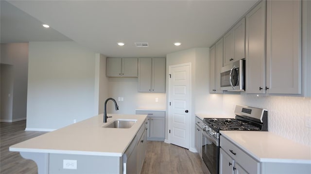 kitchen featuring light hardwood / wood-style flooring, sink, appliances with stainless steel finishes, and an island with sink