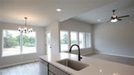 kitchen featuring ceiling fan with notable chandelier, hanging light fixtures, sink, and a wealth of natural light