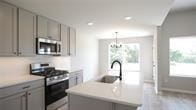 kitchen featuring a wealth of natural light, sink, stainless steel appliances, a chandelier, and a center island with sink