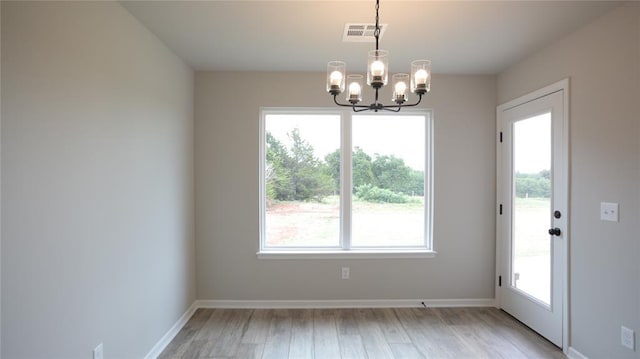 unfurnished dining area with a healthy amount of sunlight, a chandelier, and light wood-type flooring