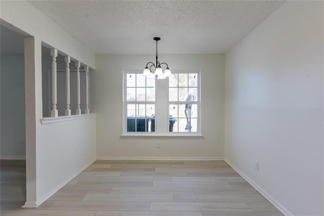 unfurnished dining area with light wood-type flooring, a textured ceiling, and a notable chandelier