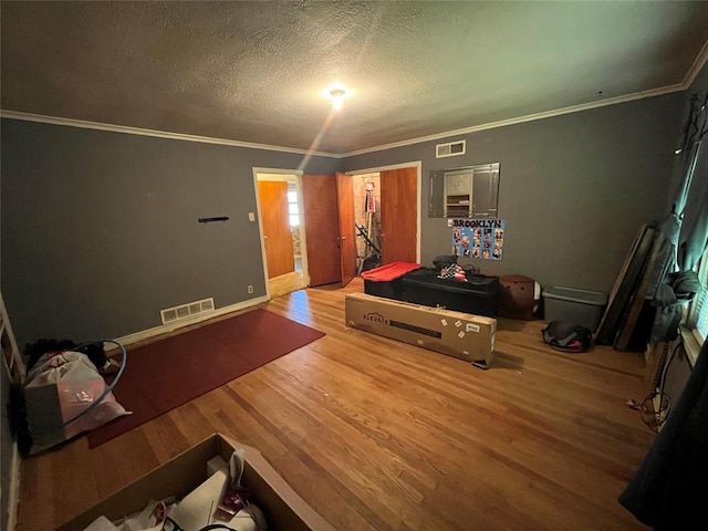 bedroom featuring hardwood / wood-style flooring, ornamental molding, and a textured ceiling