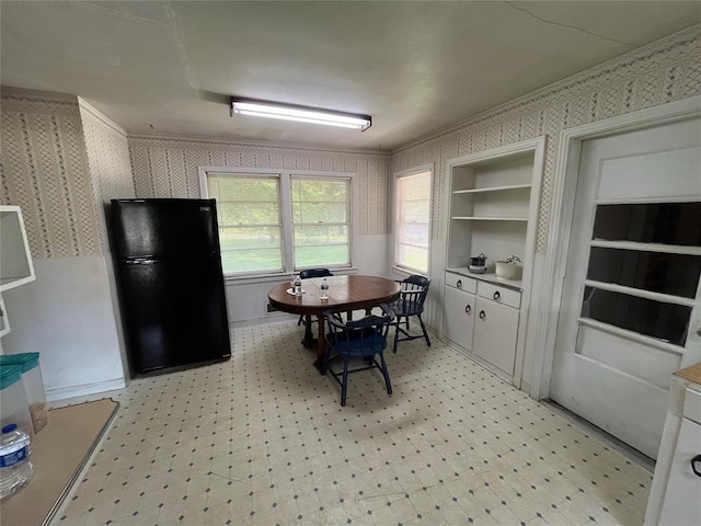 kitchen featuring white cabinets, black refrigerator, built in features, and crown molding