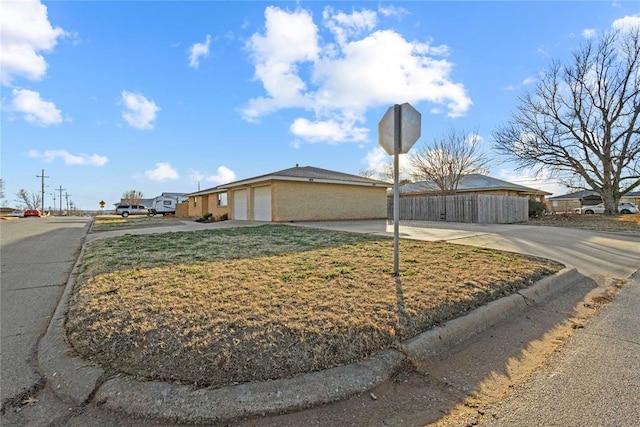 view of front of home featuring a garage, concrete driveway, and fence