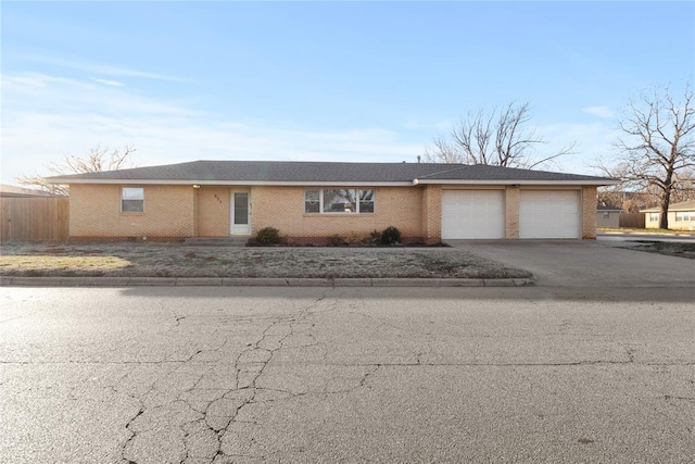 single story home with aphalt driveway, an attached garage, and brick siding