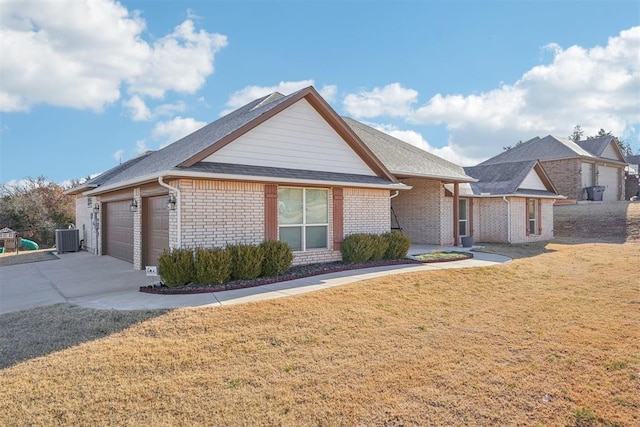 view of front of property featuring a front yard, a garage, and central AC unit