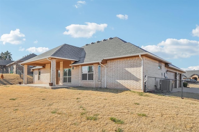 back of house featuring a lawn, a garage, and central air condition unit