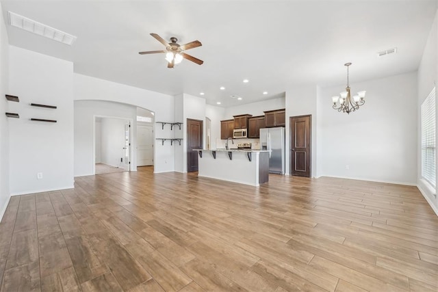 unfurnished living room with light hardwood / wood-style floors and ceiling fan with notable chandelier