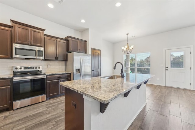 kitchen with sink, pendant lighting, a chandelier, a center island with sink, and appliances with stainless steel finishes