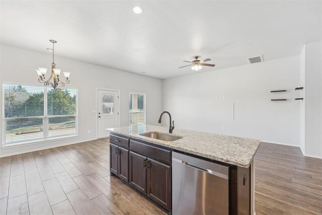 kitchen with dishwasher, sink, light stone counters, a center island with sink, and ceiling fan with notable chandelier