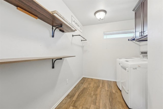 washroom with washer and clothes dryer, cabinets, and light hardwood / wood-style flooring