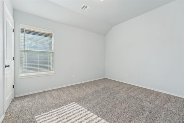 carpeted spare room featuring vaulted ceiling