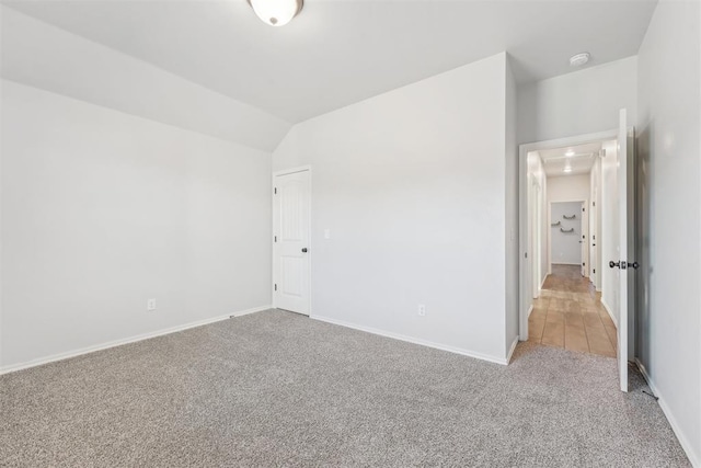 carpeted empty room featuring lofted ceiling