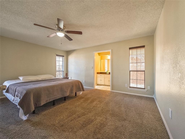 bedroom with ceiling fan, a textured ceiling, light carpet, and ensuite bath