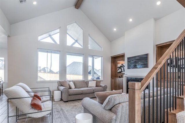 living room with a high end fireplace, beamed ceiling, wood-type flooring, and high vaulted ceiling