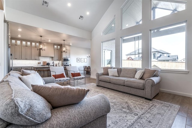 living room with a chandelier, high vaulted ceiling, and light hardwood / wood-style flooring