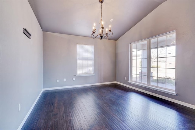 empty room with dark hardwood / wood-style flooring, a chandelier, and lofted ceiling