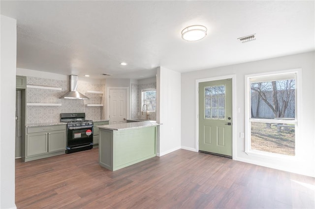 kitchen with a healthy amount of sunlight, gas stove, wall chimney range hood, and backsplash