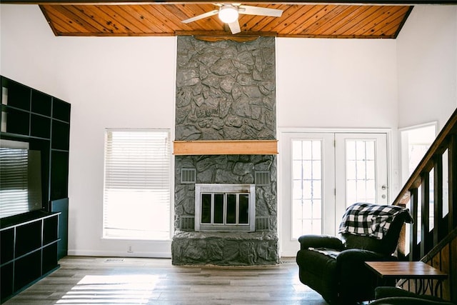 living room featuring plenty of natural light, wood-type flooring, wooden ceiling, and a fireplace