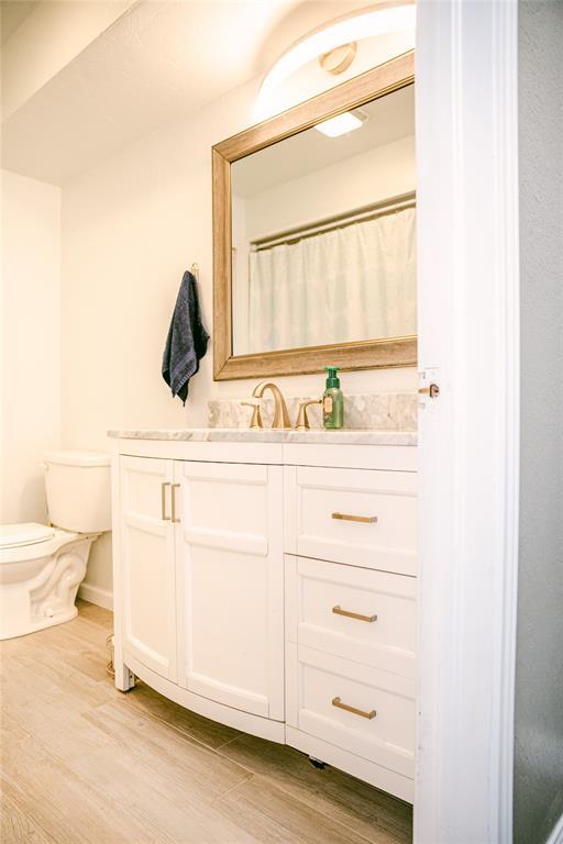 bathroom featuring wood-type flooring, vanity, and toilet