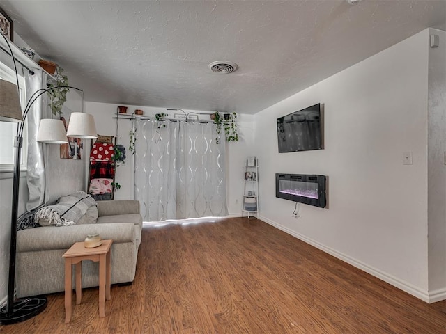 living area with heating unit, wood-type flooring, and a textured ceiling