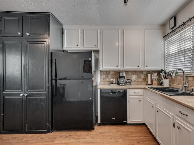 kitchen featuring sink, tasteful backsplash, black appliances, light hardwood / wood-style flooring, and white cabinets