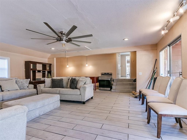 living room with a textured ceiling, ceiling fan, and a healthy amount of sunlight