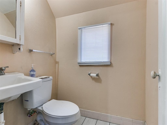 bathroom featuring tile patterned flooring, vaulted ceiling, and toilet