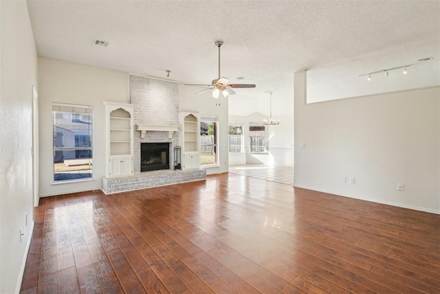 unfurnished living room with a brick fireplace, a textured ceiling, ceiling fan, dark wood-type flooring, and lofted ceiling