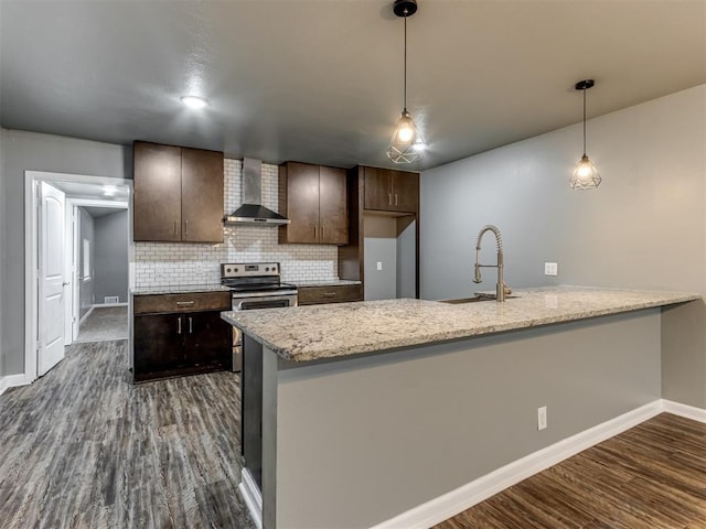 kitchen featuring pendant lighting, wall chimney range hood, sink, decorative backsplash, and stainless steel electric range oven