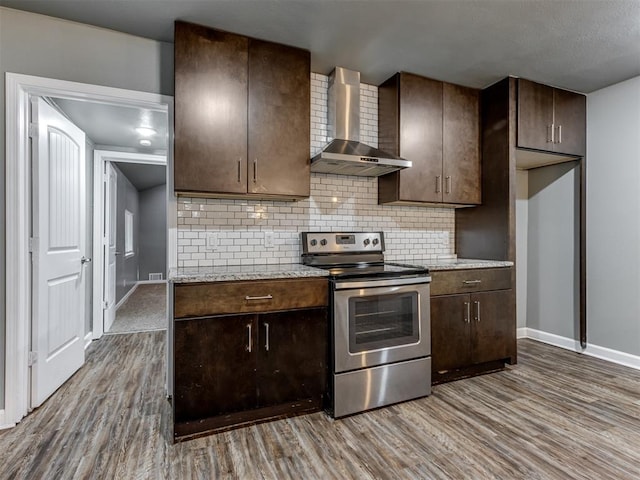 kitchen featuring stainless steel range with electric stovetop, dark brown cabinetry, wall chimney range hood, and wood-type flooring