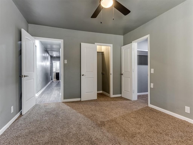 unfurnished bedroom featuring a closet, a walk in closet, carpet floors, and ceiling fan