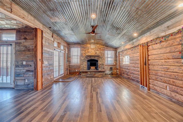 unfurnished living room featuring lofted ceiling, ceiling fan, a fireplace, rustic walls, and wood ceiling