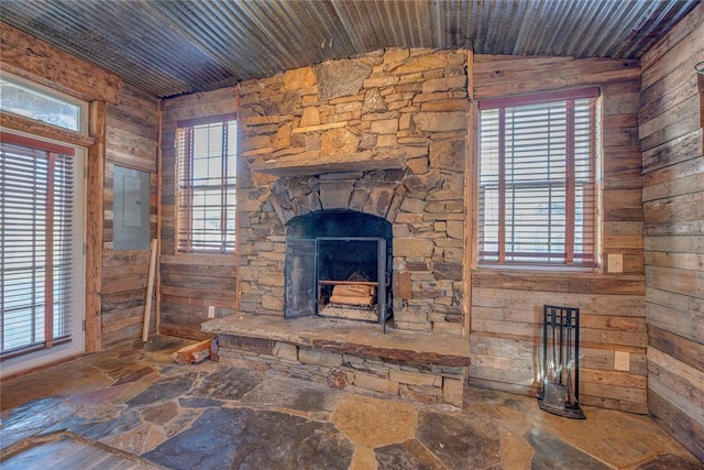 unfurnished living room with a stone fireplace, electric panel, wood walls, lofted ceiling, and wood ceiling