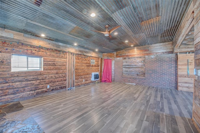 unfurnished living room with wood walls, vaulted ceiling, ceiling fan, wood ceiling, and heating unit