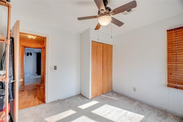 unfurnished bedroom with ceiling fan, a closet, and light carpet